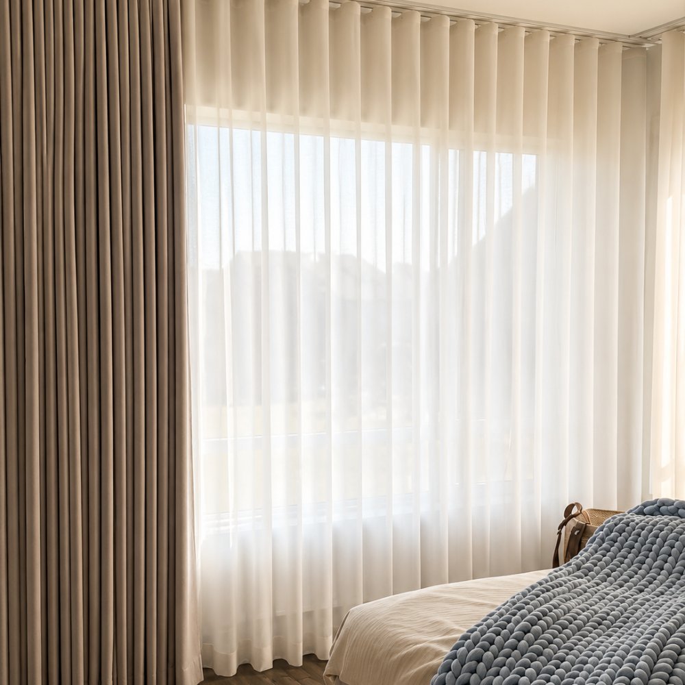 Sheer and blackout curtains layered in a bedroom